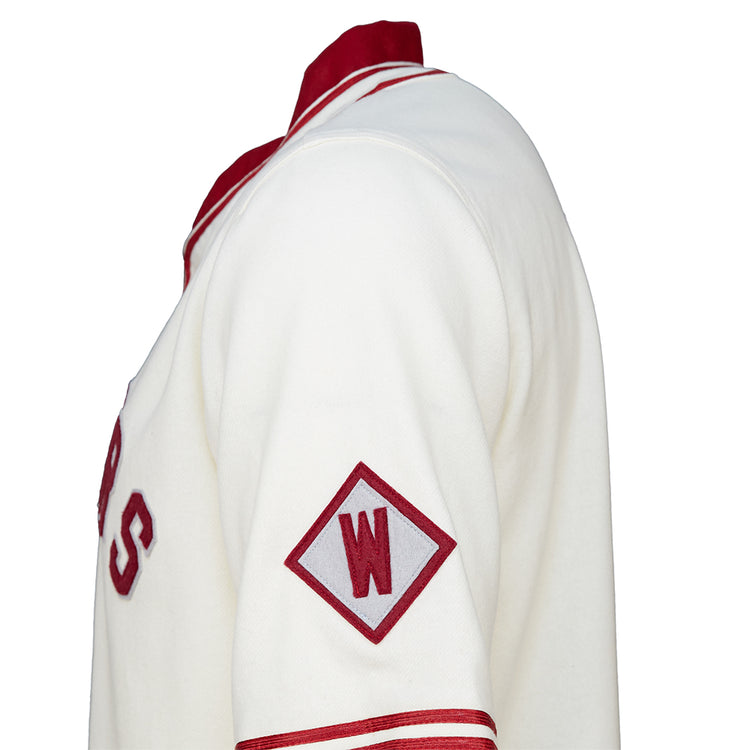 A close-up side view of the EFF Washington State University 1937 Home Jersey, showcasing white fabric with red accents, a red diamond patch with a white W on the sleeve, and classic red lettering authentic to WSU.