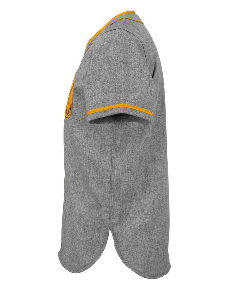 Side view of the EFF Hoboken Young Democrats 1972 Road Jersey, a short-sleeved gray button-up shirt with yellow trim on the collar and cuffs, vintage baseball style, curved hem, and a partially visible chest emblem.