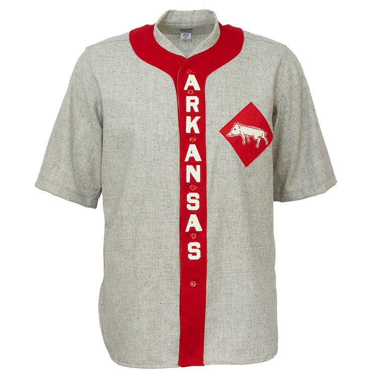 The EFF University of Arkansas 1912 Road Jersey is a gray, short-sleeve college baseball shirt with a red vertical stripe reading ARKANSAS in white and a red diamond patch featuring a white razorback logo—an authentic vintage reproduction.